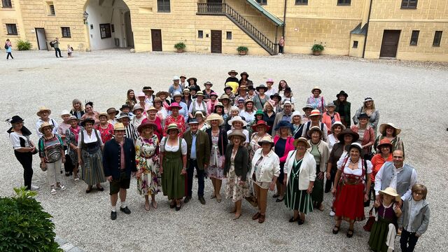 100 Frauen mit Hut und ein paar Männer im Burghof. 